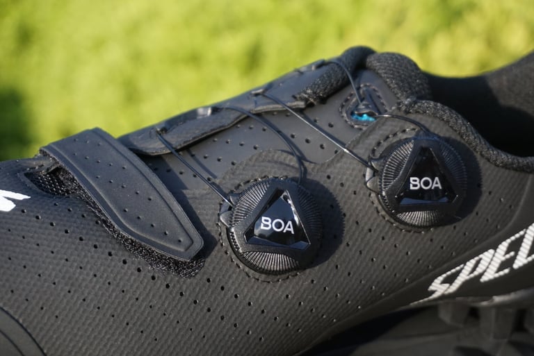 Close-up of the twin BOA dials and velcro strap on the perforated upper of a Specialized Recon 3.0 shoe.