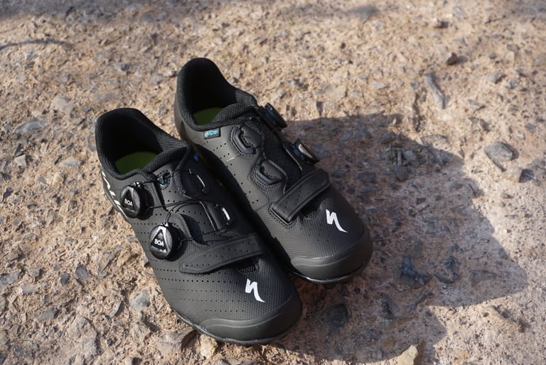 Muddy Specialized Recon 3.0 shoe on a bike pedal, seen from above beside a purple frame and bottle.