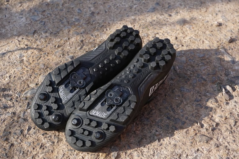 Soles of the Specialized Recon 3.0 shoes with hexagonal rubber lugs, toe stud mounts and an SPD cleat plate.