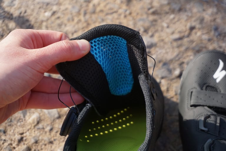 Specialized Recon 3.0 shoes seen from above on stony ground, with the green insoles and Xpel tongues showing inside.
