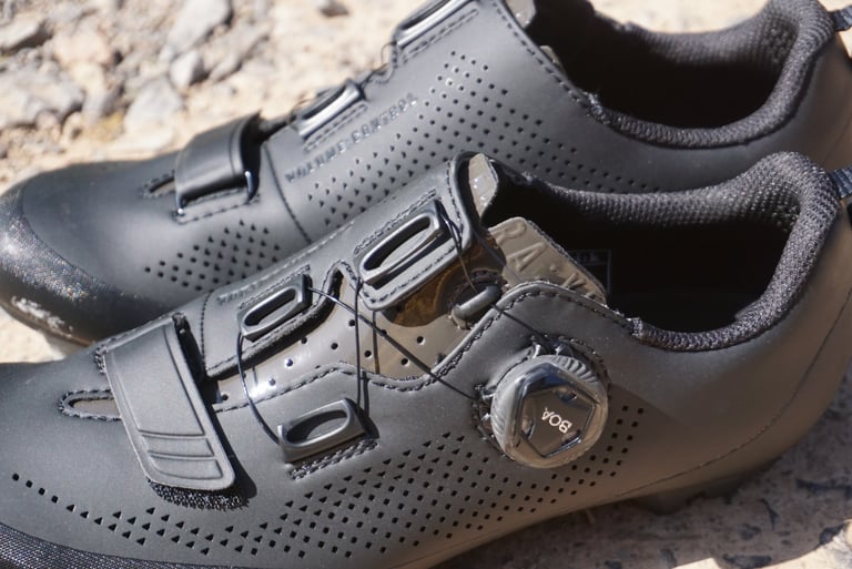 Close-up of the Fizik Terra X5's single BOA dial, lace guides and velcro toe strap on a black upper.