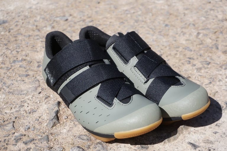 Pair of Fizik Terra Powerstrap X4 shoes from the front, showing the khaki upper, toe guard and crossing black straps.