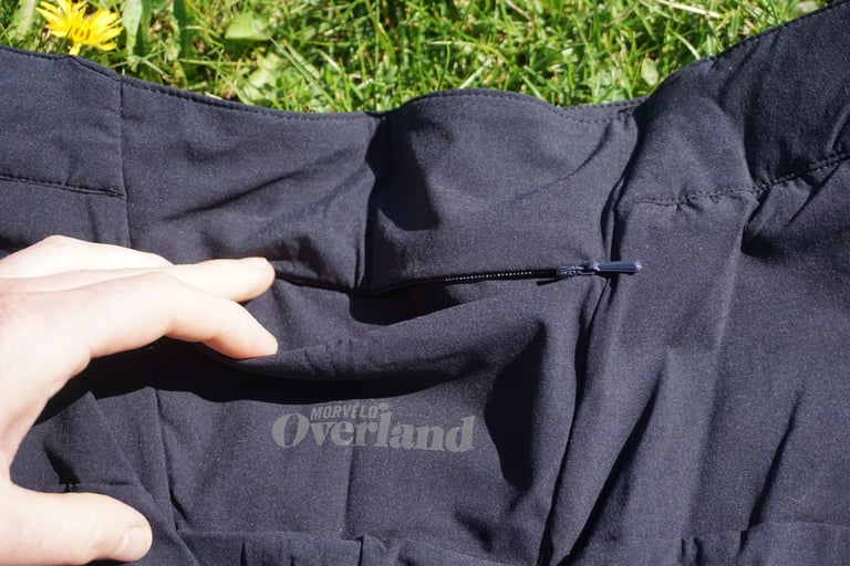 Zipped rear pocket and Morvélo Overland logo on the Selector shorts, with a hand holding the fabric.
