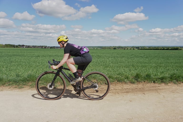 Katherine Moore rides the Specialized Diverge Comp Carbon along a dry farm track between open fields.