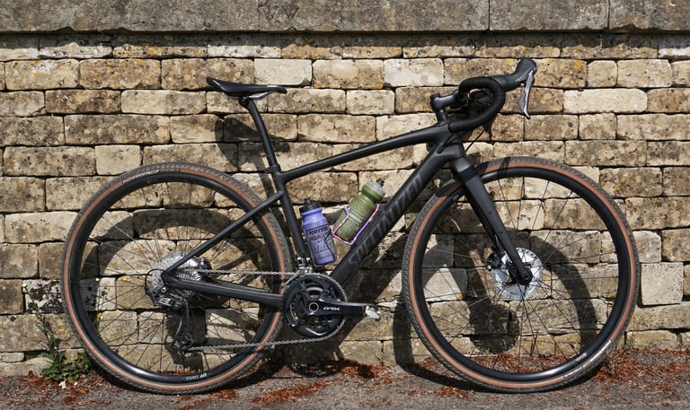 Specialized Diverge Comp Carbon with two bottles in its cages, propped against a stone wall in the sun.