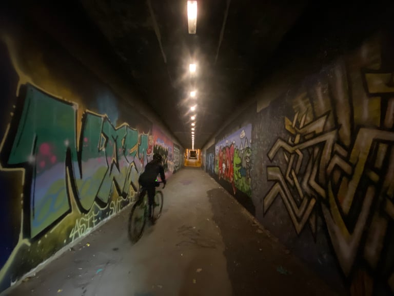 Rider on the All City Nature Boy cycles through a graffiti-covered tunnel at night.