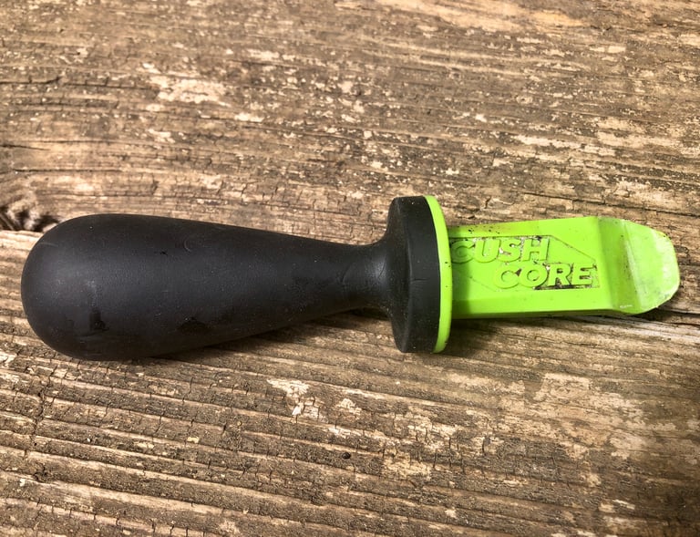 CushCore Bead Dropper tyre lever with a black rubberised handle and green plastic blade on a wooden surface.