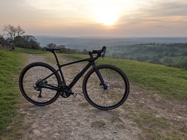 Specialized Diverge Carbon Comp on a stony hilltop track at sunset, looking over a green valley.