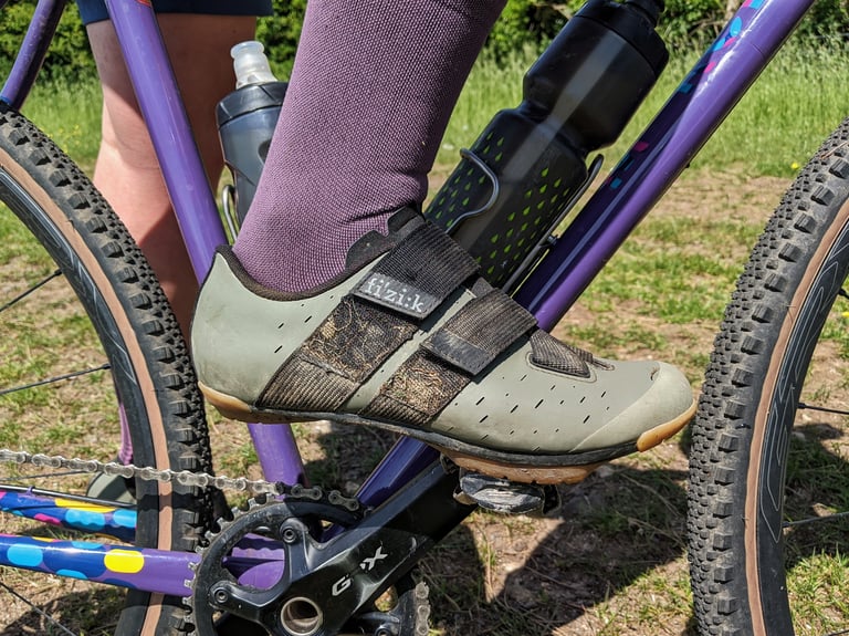 Fizik Terra Powerstrap X4 on a gravel bike pedal, with dirt and dead grass caught in the black velcro straps.