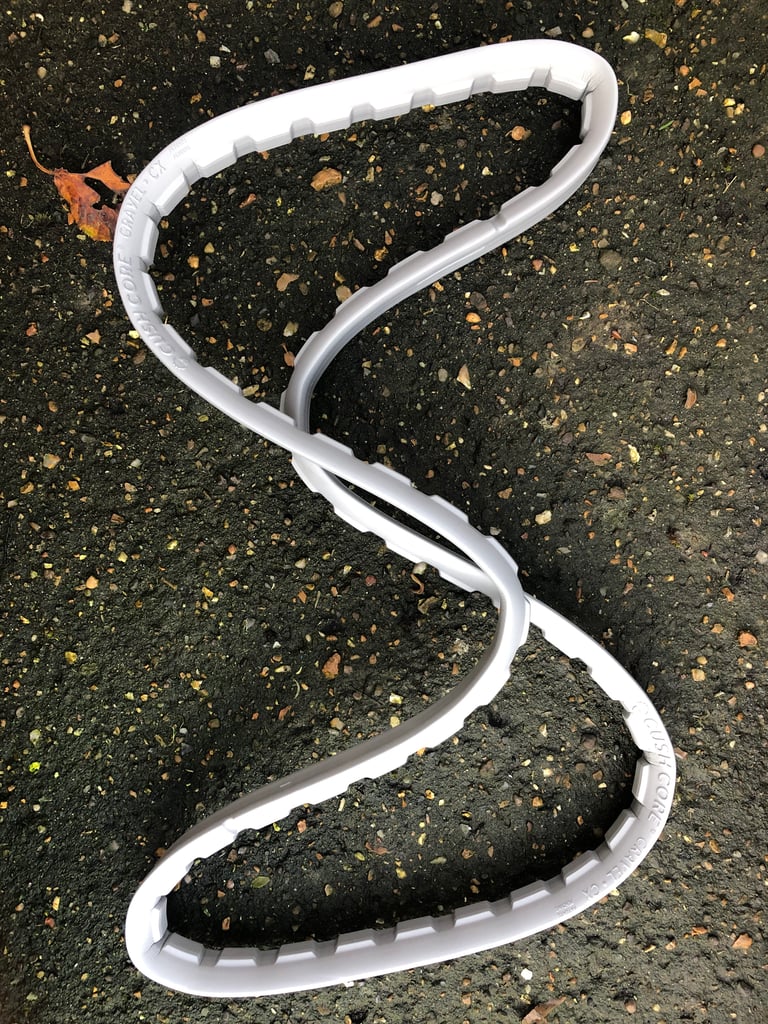Grey CushCore Gravel-CX foam tyre insert laid in an S shape on dark tarmac.