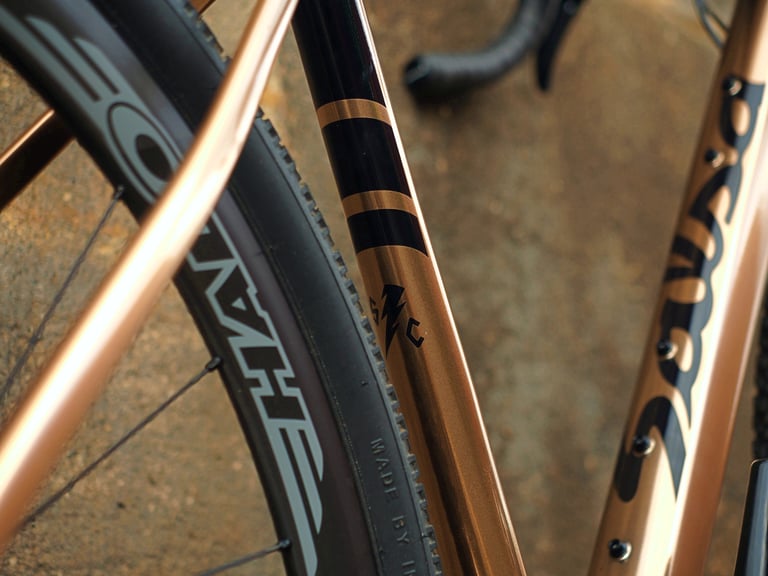 Black and gold banded seat tube of the Salsa Stormchaser, with a Halo Carbaura rim and Surly tyre beside it.