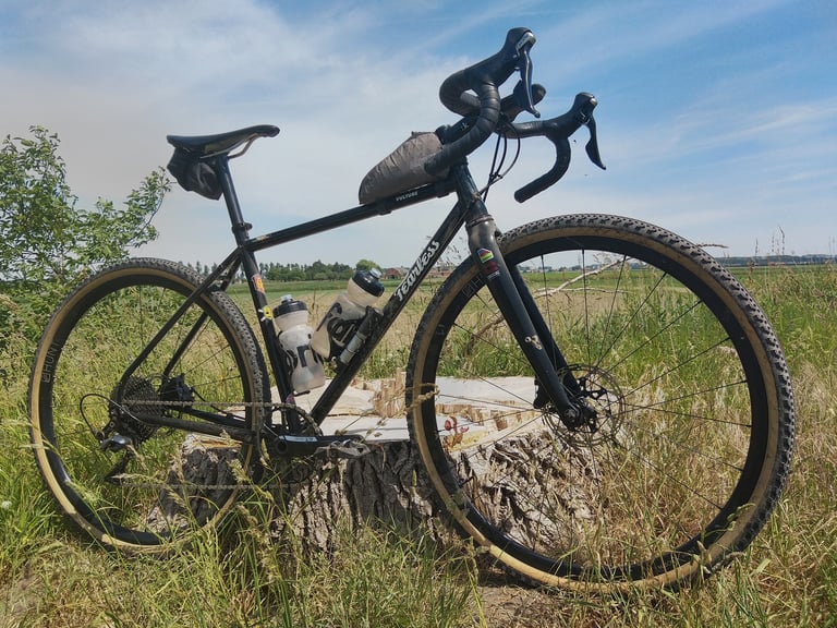 Christ Depestel's black Fearless Vulture with top tube and saddle bags, propped on a tree stump in a grassy field.