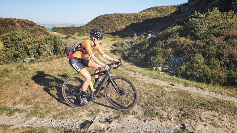 Rider in Magspeed kit spins up a gravel climb through heather and gorse on the Dirty Kanzelled Peak Edition.