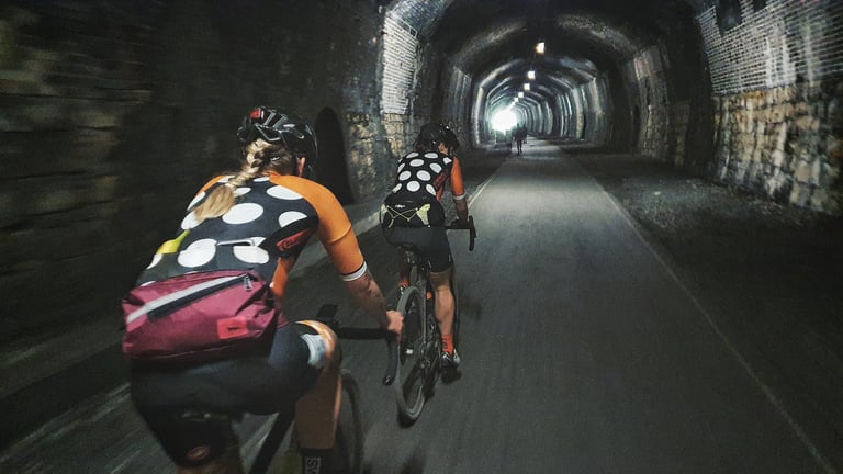 Two Magspeed riders pedal through a lit railway tunnel on the Monsal Trail during the Dirty Kanzelled ride.