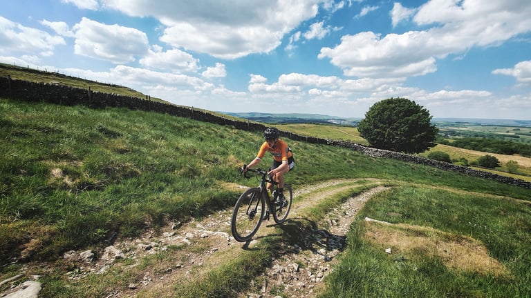 Magspeed rider on a rough stony double track beside a drystone wall on the 100-mile Dirty Kanzelled route.