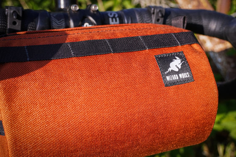 Close-up of the rust Cordura fabric and woven Wizard Works label on the Lil Presto! barrel bag.