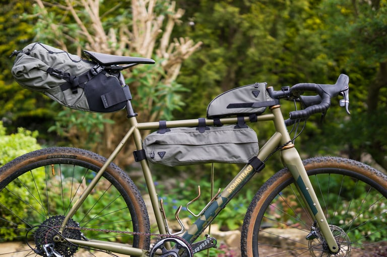 Side view of a Bombtrack gravel bike with Topeak Backloader, Midloader and Toploader bags in a garden.