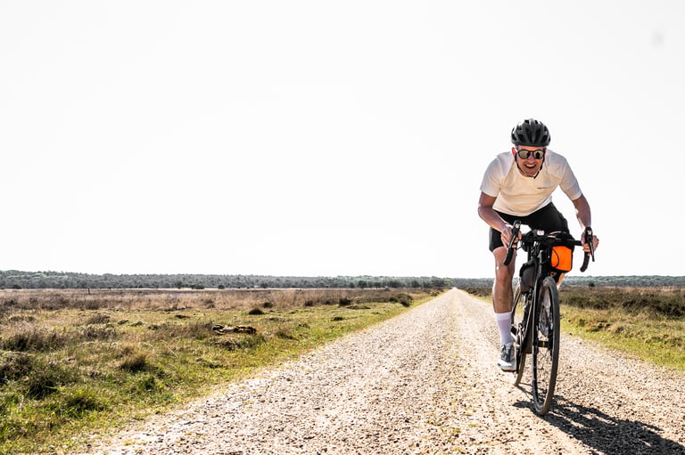 Erwin on a long straight gravel road across open heathland in the Netherlands, riding 200 miles for Dirty Kanzelled.