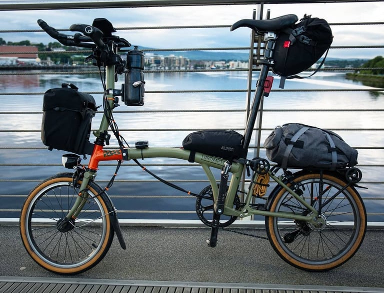 Green and orange Brompton Explore Edition set up for the TransAtlantic Way with aerobars, dynamo light and Alpkit bags.