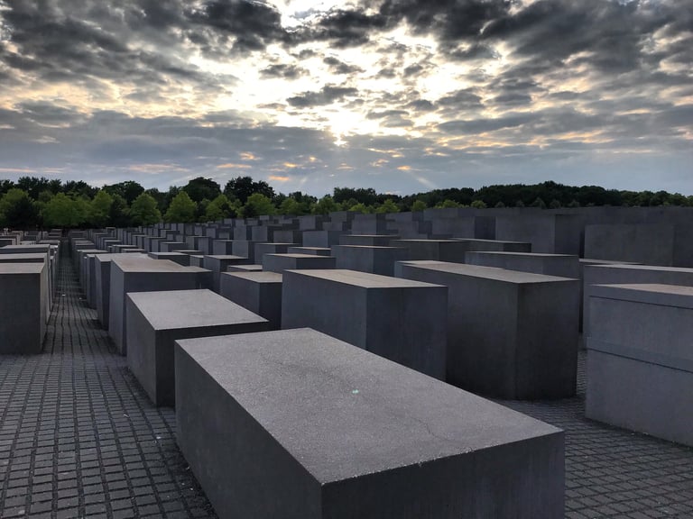 Grey concrete slabs of the Memorial to the Murdered Jews of Europe in Berlin under an evening sky.