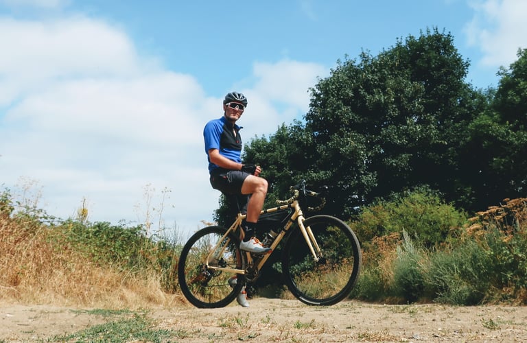 Rider sits on a cream Fearless Vulture gravel bike with a frame bag on a dry, sandy track.
