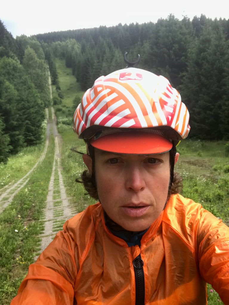 Emma Osenton, soaked in an orange rain jacket, takes a tired selfie on a panzer plate track on the Brocken in the Harz.