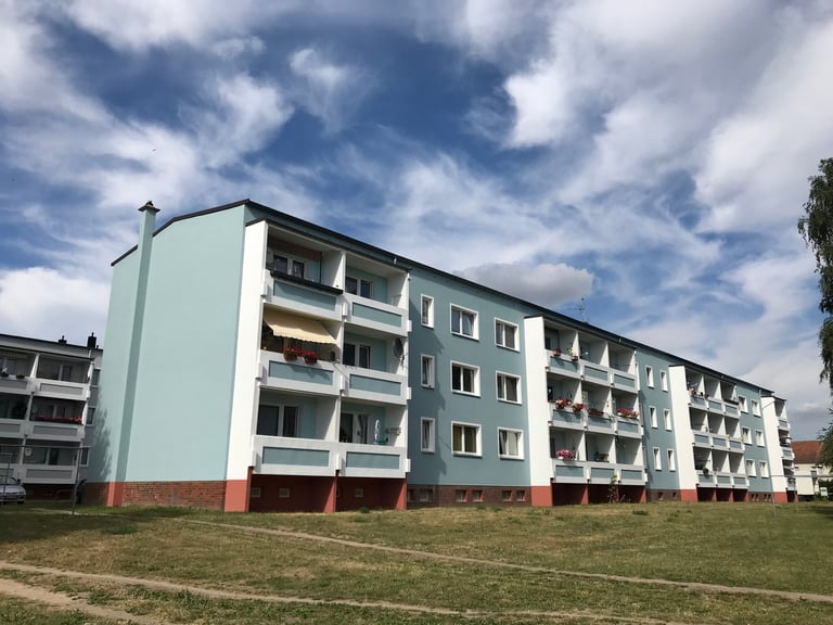 Repainted DDR-era apartment block with balconies under a cloudy sky in northern Germany.