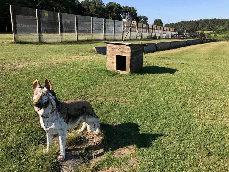 Fibreglass German shepherd and kennel beside a border fence and watchtower at Point Alpha, Germany.