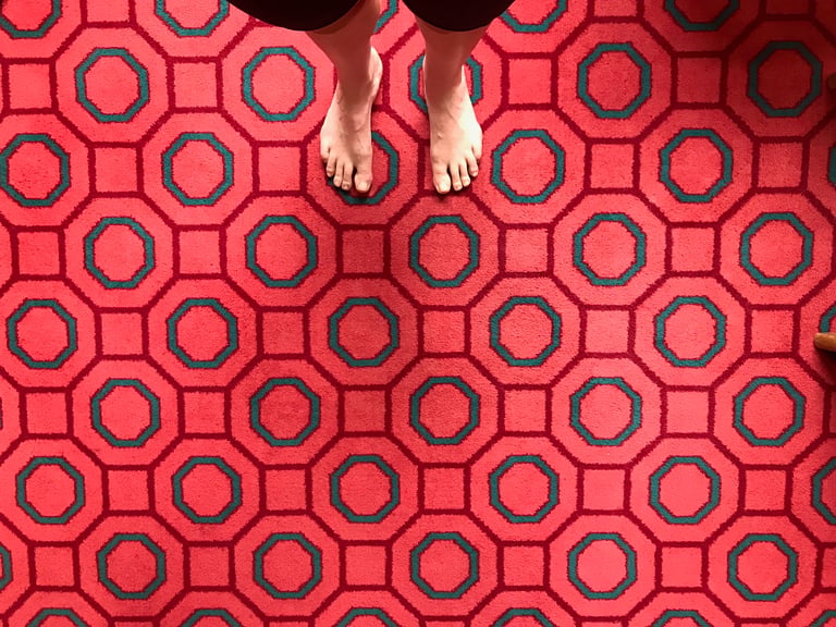 Bare feet on a red pension carpet with a green octagon pattern, Grenzsteintrophy overnight stop.