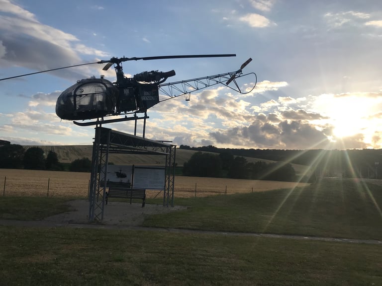 Bundesgrenzschutz helicopter mounted on a stand at the Teistungen border memorial at sunset, information board below.