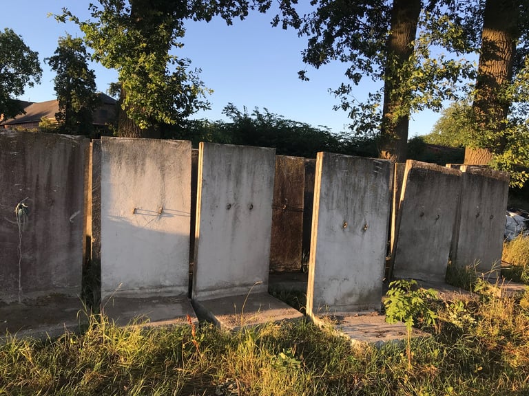 Stacked concrete wall sections from the former DDR border stored by a farm beside the Grenzsteintrophy route.