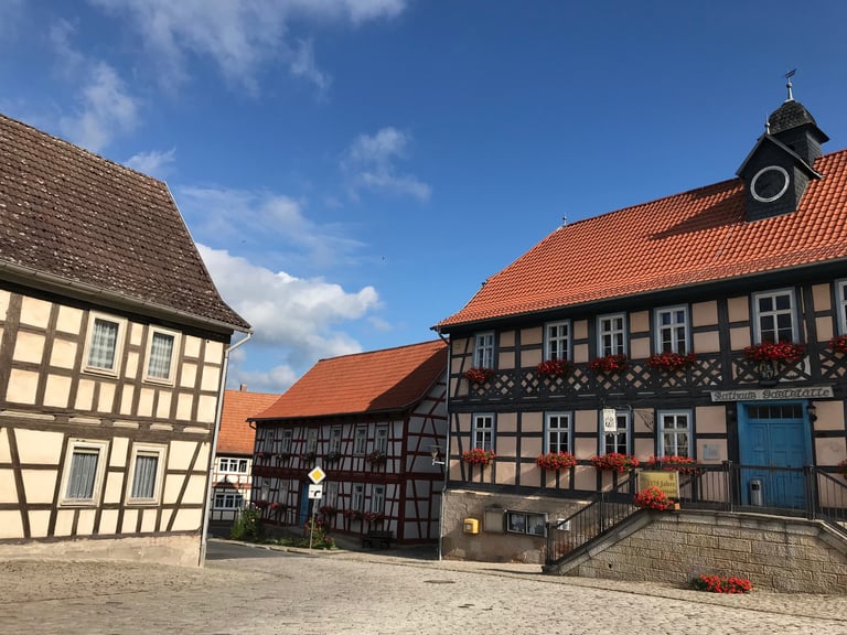 Half-timbered Rathaus in Ummerstadt, Germany, with red tiled roof and flower boxes under a blue sky.