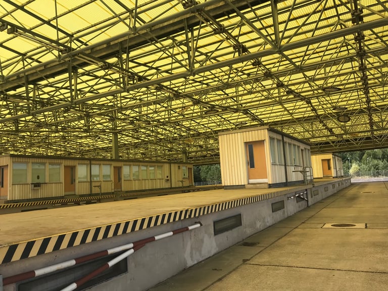 Yellow-roofed vehicle checking hall with inspection cabins and platforms at the former Marienborn border checkpoint.
