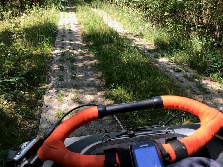 Concrete panzer plate track with grass growing through the holes, seen over the handlebars on the Grenzsteintrophy.
