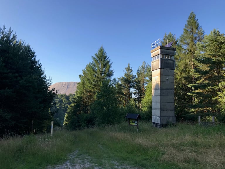 Former border watchtower in pine forest, with the salt mountain pale on the horizon on the Grenzsteintrophy.