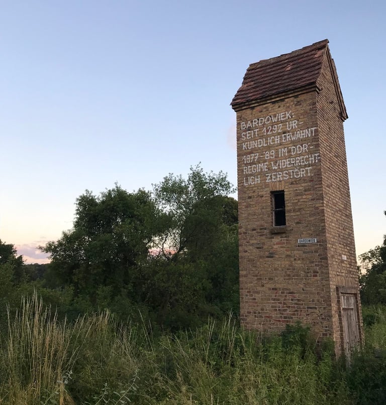 Brick tower in Bardowiek painted with text saying the village was destroyed under the DDR regime from 1977 to 1989.