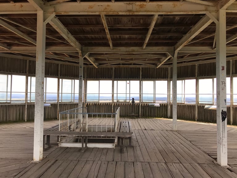 Inside the Zimmerau viewing platform, a wooden-floored room with steel posts and windows looking over the border country.