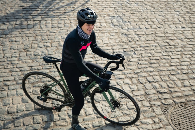 Smiling rider astride a green Santa Cruz Stigmata on a wide cobbled Belgian street, seen from above.