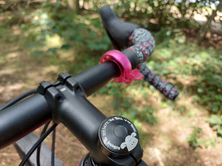 Jo Burt stem cap reading Nothing to see here, the trail's up there, on the Salsa Cutthroat's stem, with bar tape beyond.