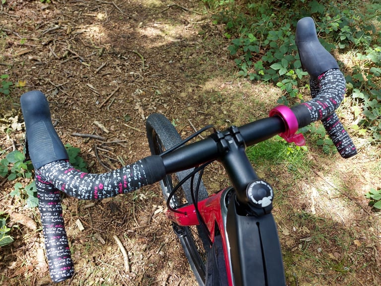 Kinesis Jo Burt signature bar tape wrapped on Salsa Cowchipper flared drops, seen from the saddle on a woodland path.