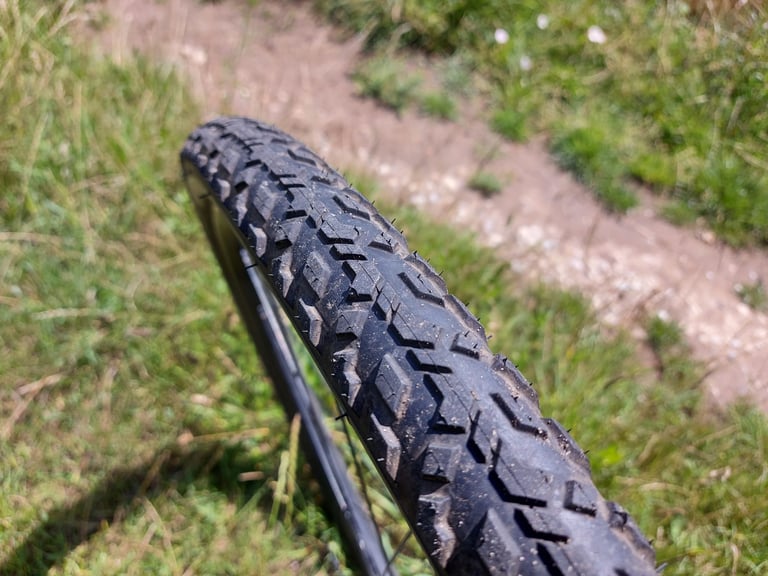 Tread of the Pirelli Cinturato Gravel M, with its central ridge and angled side knobs, on a dry trail.