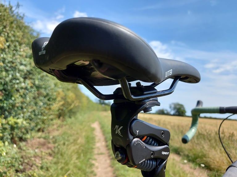 Cirrus Cycles Kinekt seatpost from behind the WTB saddle, showing the preload bolt and numbered sag guide on the linkage.