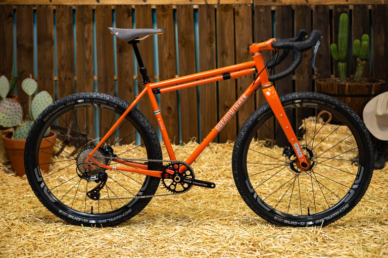 Breadwinner B-Road steel gravel bike in glossy orange with ENVE wheels and Schwalbe G-One tyres.