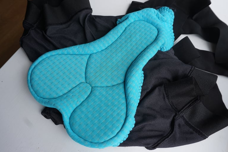 Blue chamois pad inside the Velocio women's Mesh TRAIL Bib Liner, laid on black mesh fabric.