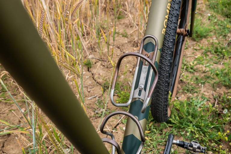 Silca titanium bottle cages in bourbon finish on the Bombtrack Hook EXT down tube, beside a pedal.