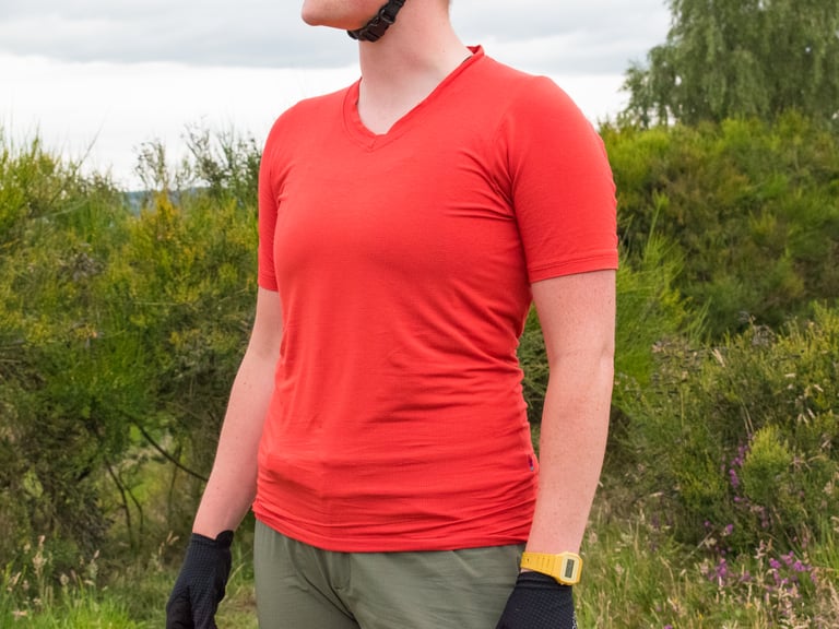 Velocio women's Micromodal Trail Tee in Lava Red, front view, with V-neck and olive shorts.