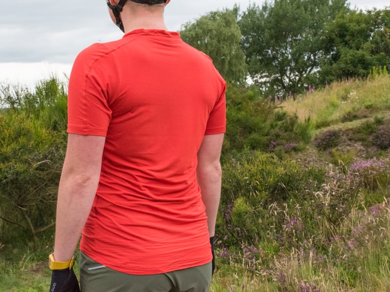 Rear view of the Velocio Micromodal Trail Tee in Lava Red, showing the longer dropped hem at the back.