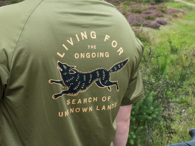 Back of the Cascada Trail Tee with a leaping wolf and the words 'Living for the ongoing, search of unknown lands'.
