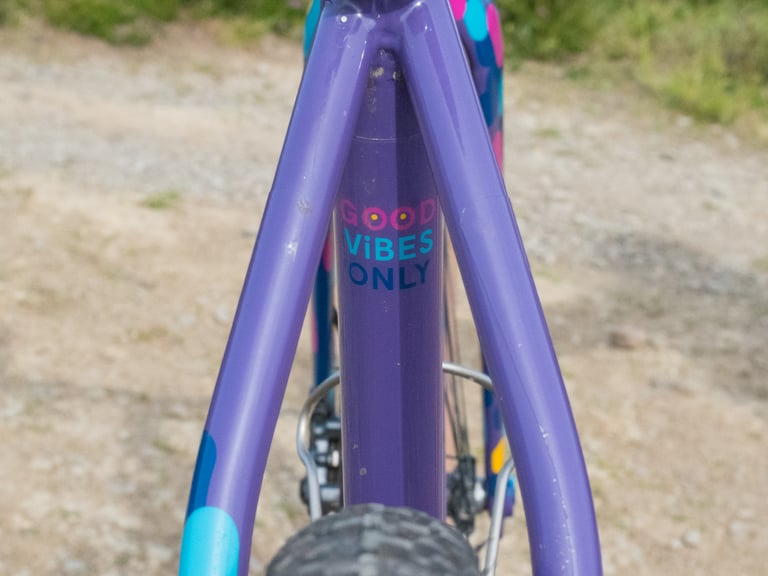 Good Vibes Only sticker on the seat tube of Katherine's purple Mercredi steel frame, seen from behind.