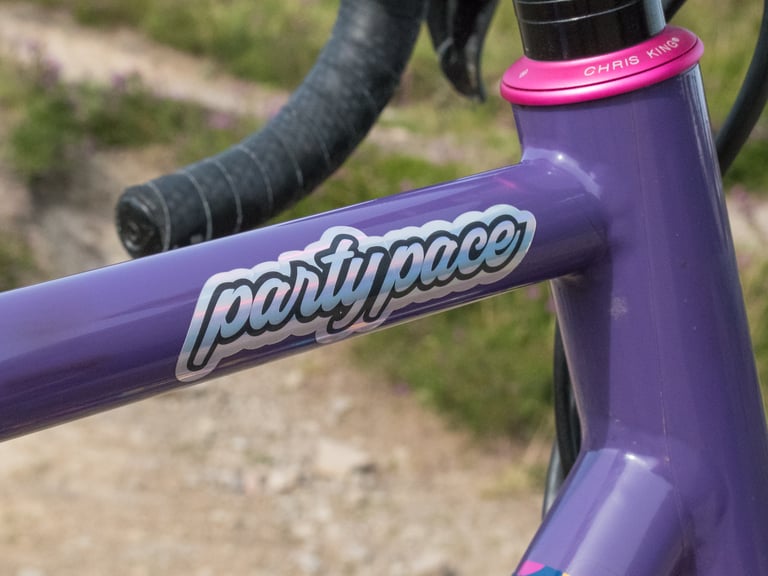 Party Pace sticker on the purple top tube of Katherine's Mercredi, beside the pink Chris King headset.